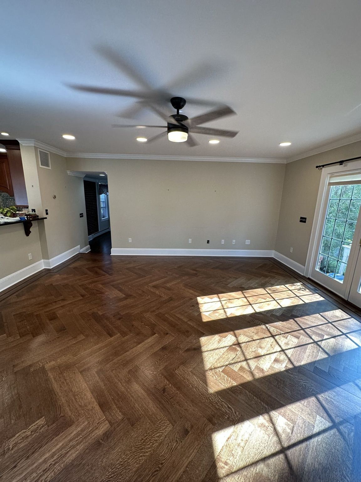 Finished herringbone floor with sunlight patterns across the completed room
